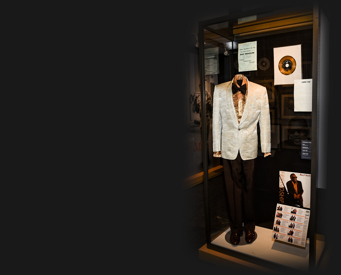 A white suit with gold dress shirt and black tie and pants worn by Ray Charles on display at museum